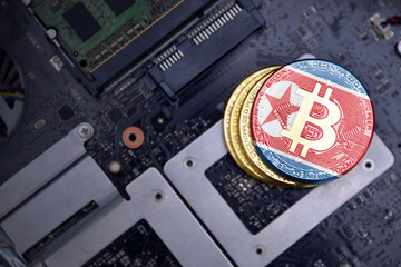 golden bitcoins with flag of north korea on a computer electronic circuit board. bitcoin mining...