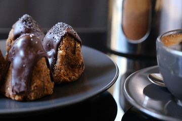 Anthill chocolate cake dessert on a gray plate and cup of coffee. Black table in the kitchen.