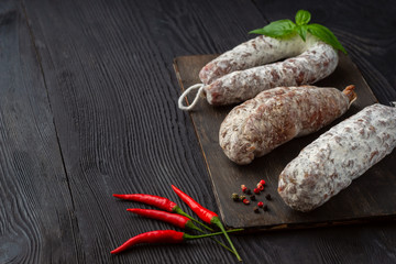 Aromatic regional pork sausage lying on a wooden board on black wooden  background