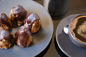 Anthill chocolate cake dessert on a gray plate and cup of coffee. Black table in the kitchen.