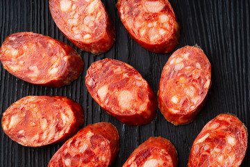 A french saucisson - dry summer sausage on the black background.