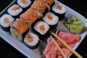 Sushi roll with seafood and soy sauce, wasabi and ginger. Sushi roll with salmon on a black background.