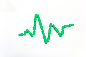 A pulse is by green pills Isolated on white background. Medicine concept.