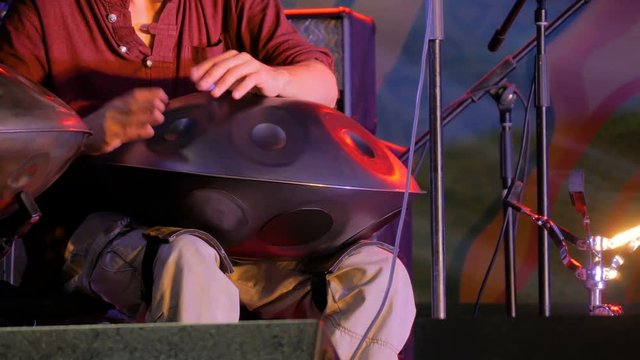 Man playing tank drum or hang on stage of ethnic open air concert. Relaxation, folk, meditative and traditional ethnic music concept