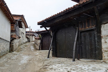 Authentic unique residential district with painted in bright colors houses, stone  walls, wooden windows, verandahs and picturesque eaves in snowfall, Koprivshtitsa town, Bulgaria, Europe  