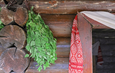 Birch broom on the background of a log Russian hut.
