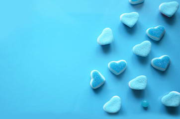 Fototapeta na wymiar An assortment of colourful, festive sweets, lue marmalade in the shape of a heart on a blue background with a variety of caramels and candies, marshmallows. Abstract background. top view . copy space.