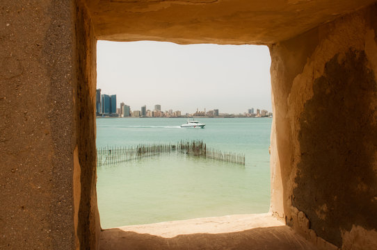 View of the sea with boat and  Bahrain skyline from Bu Maher Fort in Bahrain on Muharraq Island. Also known as Qal'at Bu Maher which can be reached by boat from Bahrain National Museum.