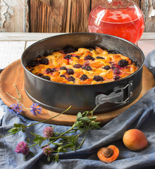Homemade cake with blackberries, apricots, gooseberries. Cake stands in a metal baking dish on a...