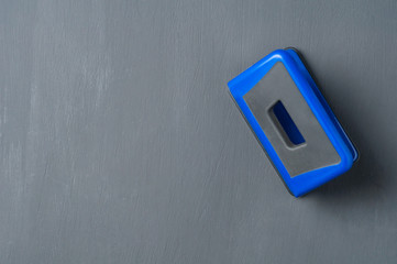 One new metal blue hole puncher on black concrete table. Copy space for text