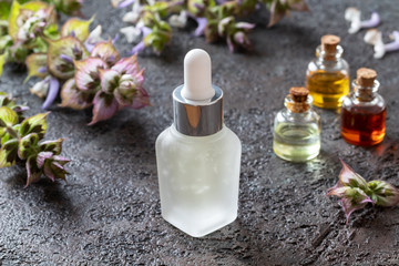 A bottle of clary sage essential oil with fresh plant