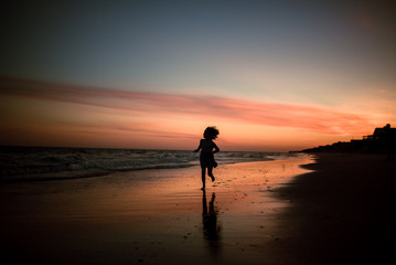 Fototapeta na wymiar child running on beach at sunset 
