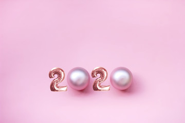 new year 2020. festive background, minimalism, space for text. top view. pink background, figures and pearl Christmas toys