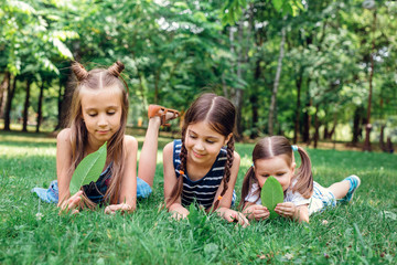 Fototapeta premium Kids playing in park. Three little girls laying on green fresh grass