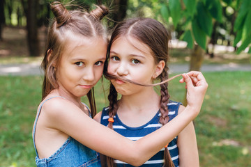 Two cute little girls having fun in park in sunny summer day