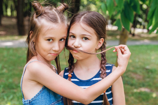 Two cute little girls having fun in park in sunny summer day