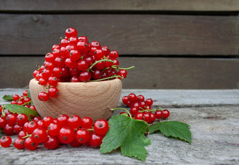  Red currants in a wooden bowl on a background of wooden boards
