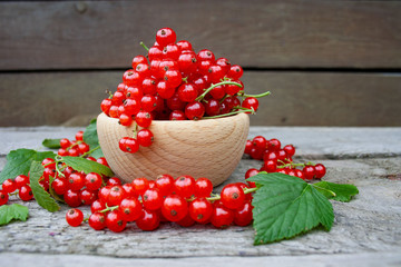 Red currants in a wooden bowl on a background of wooden boards