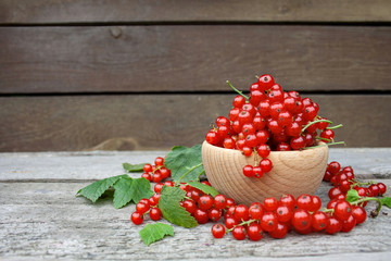 Czerwone porzeczki w drewnianej miseczce na tle desek