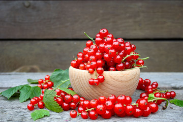 Czerwone porzeczki w drewnianej miseczce na tle desek