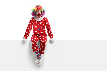 Surprised clown sitting on a white billboard