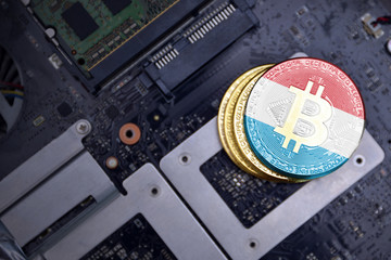 golden bitcoins with flag of luxembourg on a computer electronic circuit board. bitcoin mining...