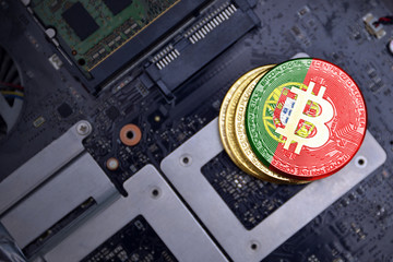 golden bitcoins with flag of portugal on a computer electronic circuit board. bitcoin mining...