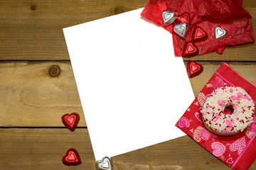 White paper on a Valentine's Day Background with chocolates and a donut on wood