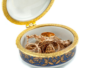 Small ceramic box with gold jewelry in it on white background