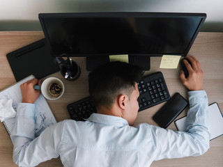 Top view of a young male worker or employee fell asleep on the keyboard at his workplace in office....