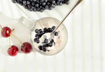 homemade yogurt with berries (blueberries, sweet cherry) on a white background, top view
