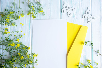 Mock up template with envelope, postcard and small yellow wildflowers. Frame for congratulatory colors with wildflowers. Flat lay, top view.