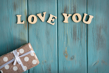 The inscription love you. The basis for the banner with the inscription love you on a blue background. Greeting card design for a loved one with a present box