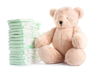 Stack of diapers and teddy bear on white background. Baby accessories