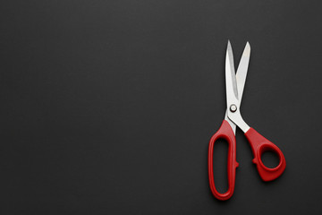 Pair of sharp scissors on dark background, top view. Space for text