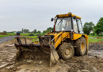 A yellow tractor building a new house in a wet weather