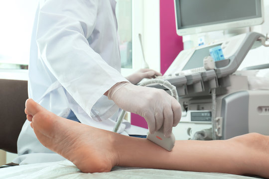 Doctor conducting ultrasound examination of patient's leg in clinic, closeup