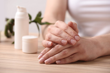 Obraz na płótnie Canvas Young woman showing hands with smooth skin at wooden table, closeup