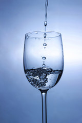 Transparent liquid (water) splash micro wave inside the wine glass on a white background