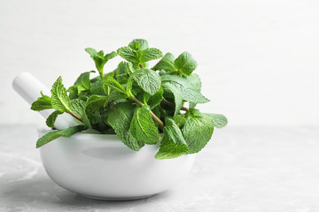 Mortar with fresh green mint and pestle on table