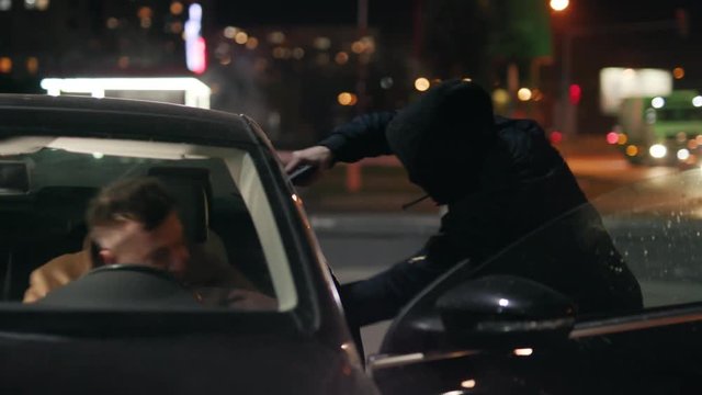 Close up gangster with gun attacked a man in a car at night street thief lady criminal assault bandit burglar danger dangerous parking people risk rob robber desperation armed auto illegal pistol
