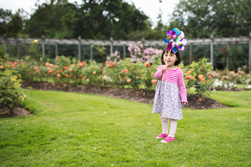 toddler girl play pinwheel toy  in  Summer garden