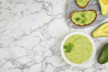 Flat lay composition with guacamole, sandwiches and avocados on white marble table. Space for text