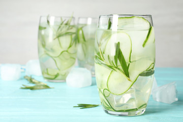 Glasses of refreshing cucumber lemonade on light blue table, space for text. Summer drink