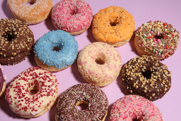 assorted donuts with chocolate frosted, pink glazed and sprinkles donuts.