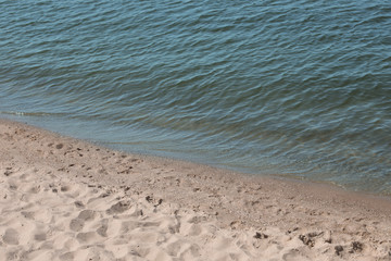 View of sea water and beach sand on sunny summer day