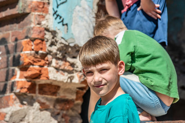 Obraz na płótnie Canvas Poor orphans against the background of destroyed buildings, the concept of the life of street children. Staged photo.