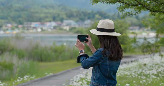 Woman take photo with cellphone in countryside
