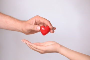 Man giving red heart to woman on white background, closeup. Donation concept