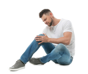 Full length portrait of man with knee problems sitting on white background